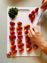 High angle view of hand holding strawberries on table