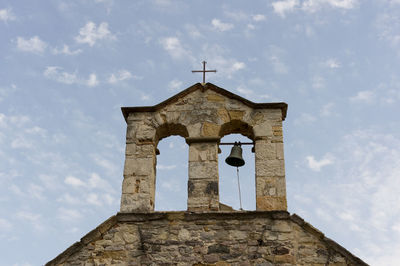 Low angle view of cross on building against sky