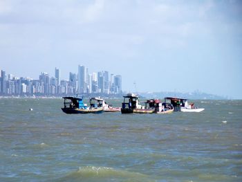 Boats in sea against buildings in city