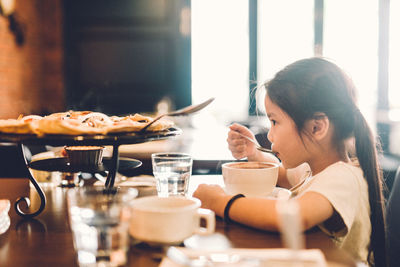 Side view of woman with coffee served on table in restaurant