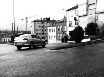 Cars on street by buildings in city against sky