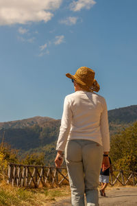 Rear view of woman standing on landscape against sky