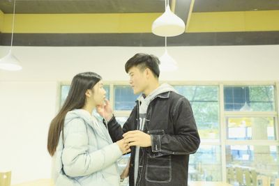 Side view of young couple standing against wall