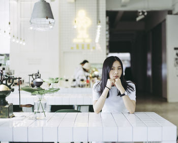 Portrait of young woman sitting at table in restaurant