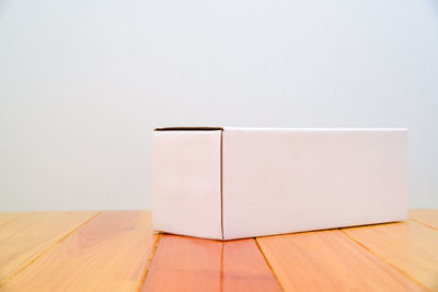 Close-up of wooden table against white wall