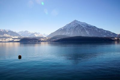 Scenic view of sea and mountains against clear blue sky