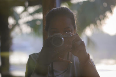 Woman photographing with camera against trees