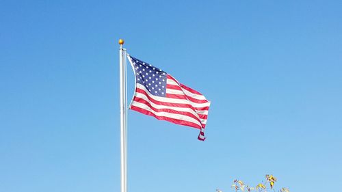 Low angle view of american flag against clear blue sky