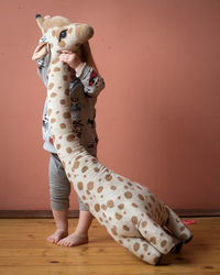 Full length of boy with toy on hardwood floor against wall