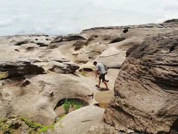 Full length of man walking on rocks against sky