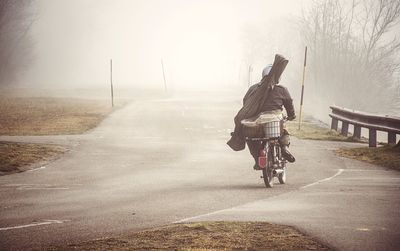 Rear view of man riding bicycle on road