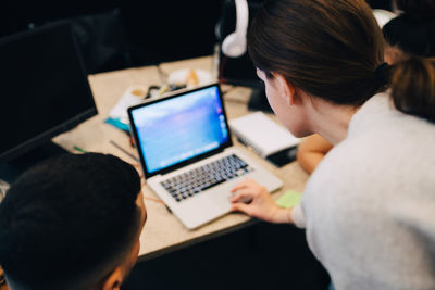 High angle view of businesswoman using laptop amidst colleagues at creative office