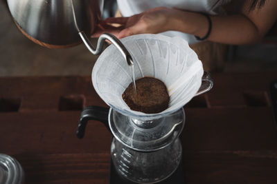 Cropped image of hand pouring coffee in cup