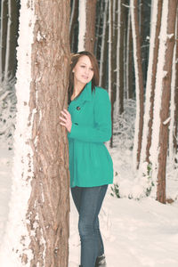 Woman standing on tree trunk during winter