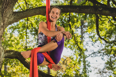 Low angle portrait of young woman doing acrobatic activity with fabric