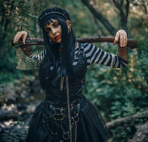Portrait of young woman standing against trees