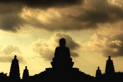 Low angle view of silhouette built structures against cloudy sky