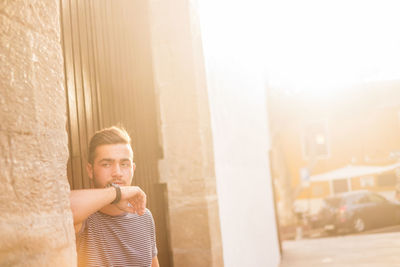 Thoughtful young man leaning on wall against door