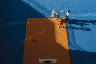 Directly above shot of pre-adolescent girls enjoying while playing at basketball court