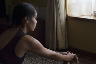 Side view of young woman sitting at home