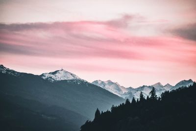 Scenic view of snowcapped mountains against cloudy sky during sunset