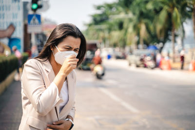 Woman coughing on street in city