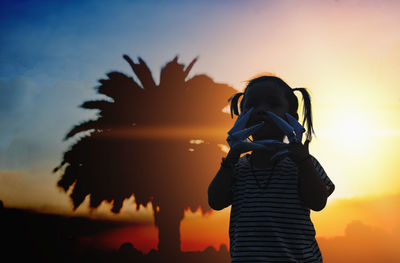 Silhouette woman standing against sky during sunset