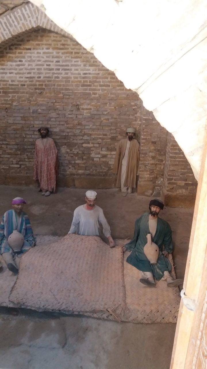 GROUP OF PEOPLE SITTING AGAINST WALL