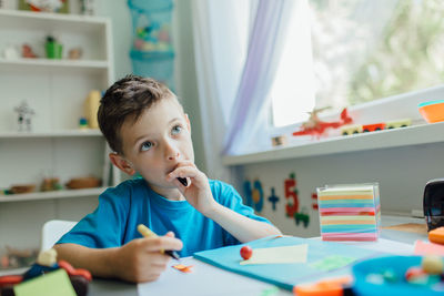 Portrait of boy sitting on table at home