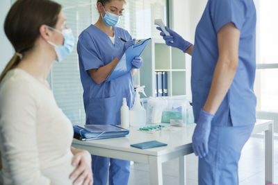 Female doctors discussing by patient in clinic