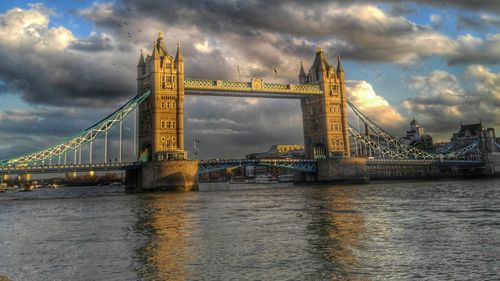 Bridge over river against cloudy sky