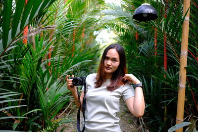 Young woman standing against plants