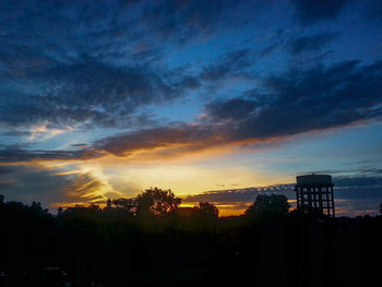 Silhouette trees and buildings against sky during sunset