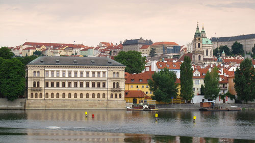 Buildings by river against sky