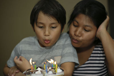 Close-up of mother and son blowing birthday candles