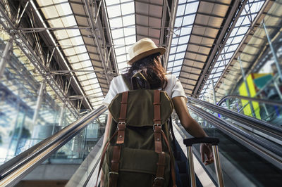 Rear view of woman standing on escalator at airport
