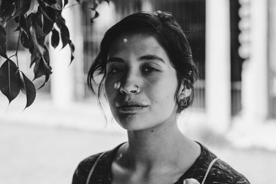 Close-up portrait of beautiful woman standing by leaves