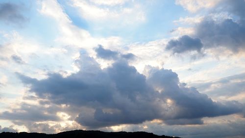 Low angle view of sunlight streaming through clouds