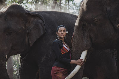 Smiling woman standing with elephant in forest