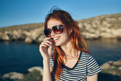 Portrait of young woman wearing sunglasses against sky