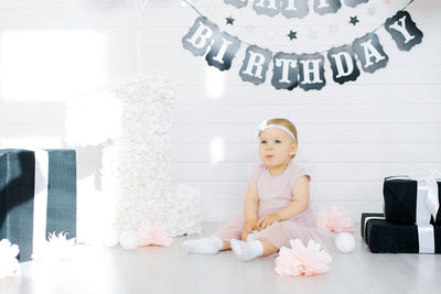 The birthday girl 1 year old sits on the photo zone and holds a ball in her hands