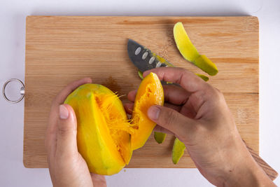 Midsection of person holding fruits on cutting board