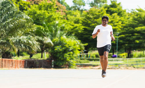 Full length of man running on road against tree