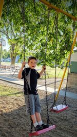 Full length portrait of boy on swing at park