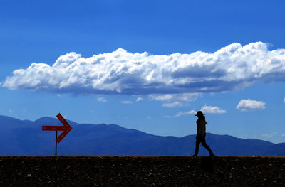 Silhouette woman walking on field against mountain ranges