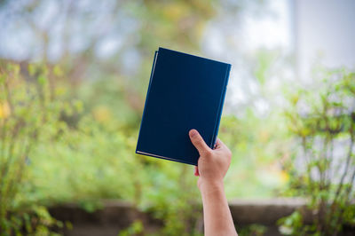 Close-up of person holding book outdoors