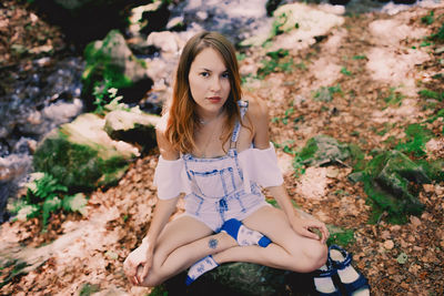 Beautiful young girl meditating doing yoga outdoors in summer forest near the stream