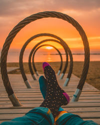 Low section of man relaxing at beach during sunset