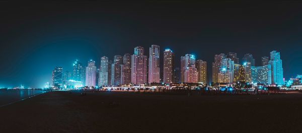 Illuminated modern buildings against sky at night