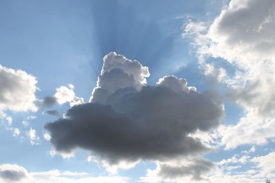 Low angle view of sunlight streaming through clouds